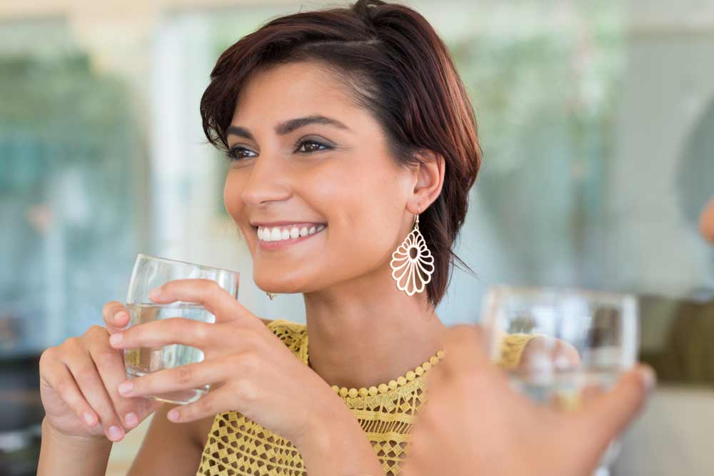 woman smiling while holding a glass of water