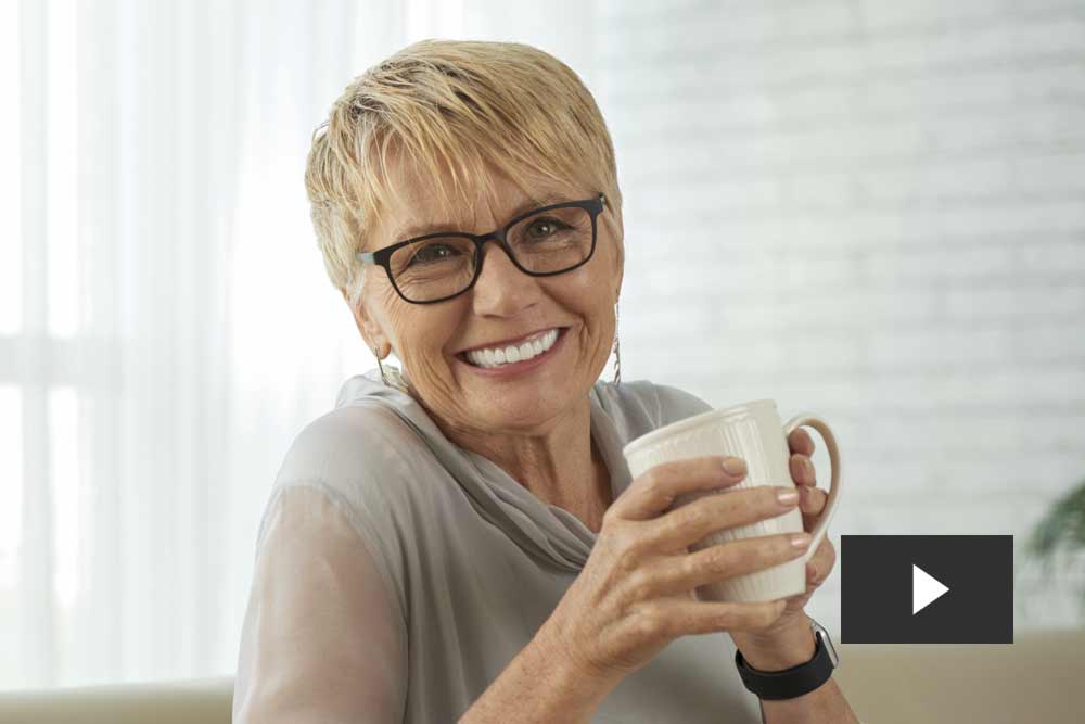 Older woman holding a mug and smiling video play button